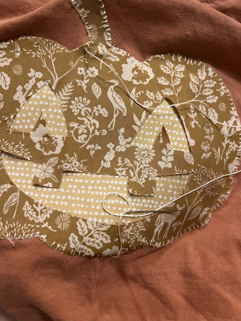 Pumpkin applique being hand stitched on a t shirt 