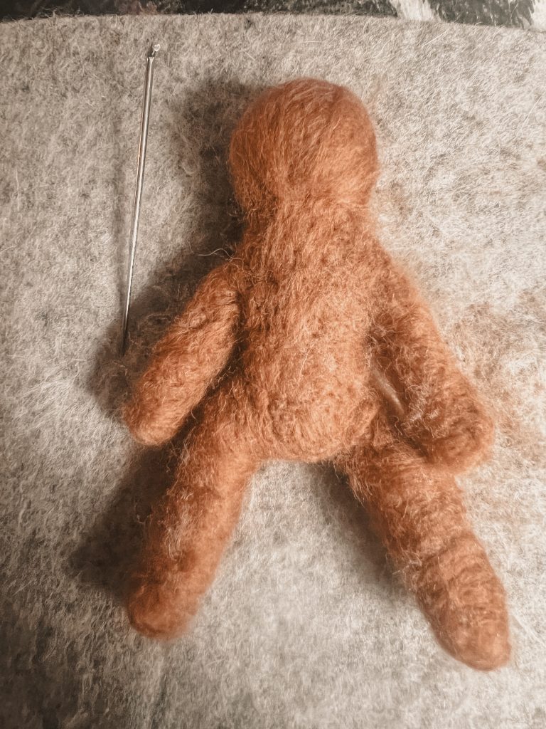 Basic needle felted sculpture of a gingerbread man without any facial details . How to needle felt a gingerbread man