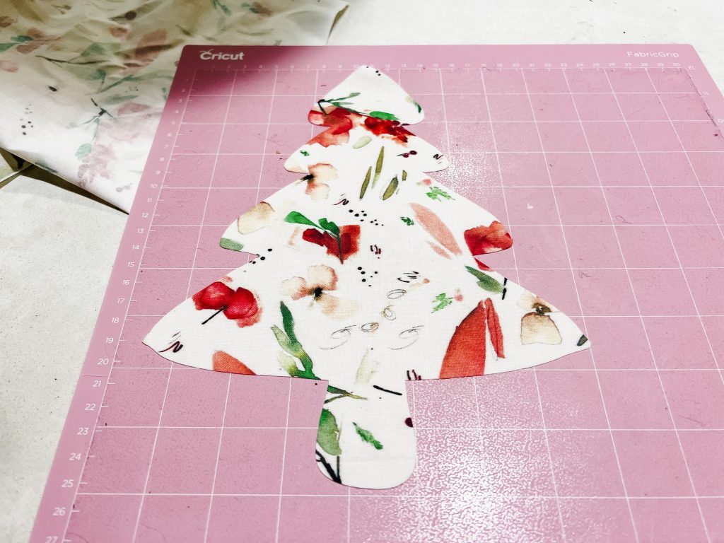 A Christmas tree silhouette cut out of floral Christmas fabric using the cricut maker 3