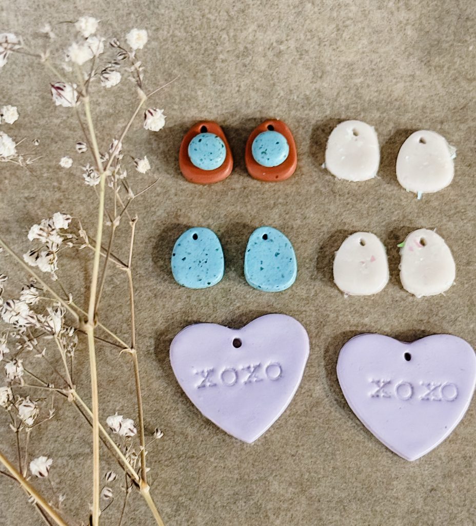 Sculpey premo polymer clay earrings on a baking sheet prepared with parchment paper. Polymer clay earrings preparing to go in the oven to bake.