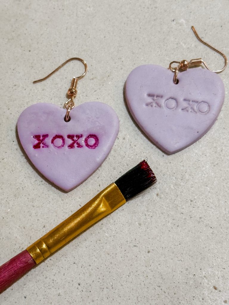 Purple polymer clay heart earrings being painted red