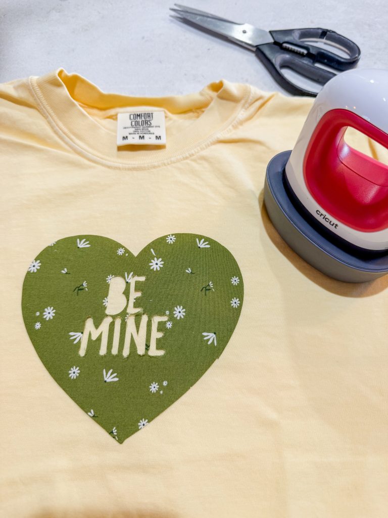 Fabric applique shirt for Valentine’s Day with a green heart that says ‘be mine’ and an easy press mini
