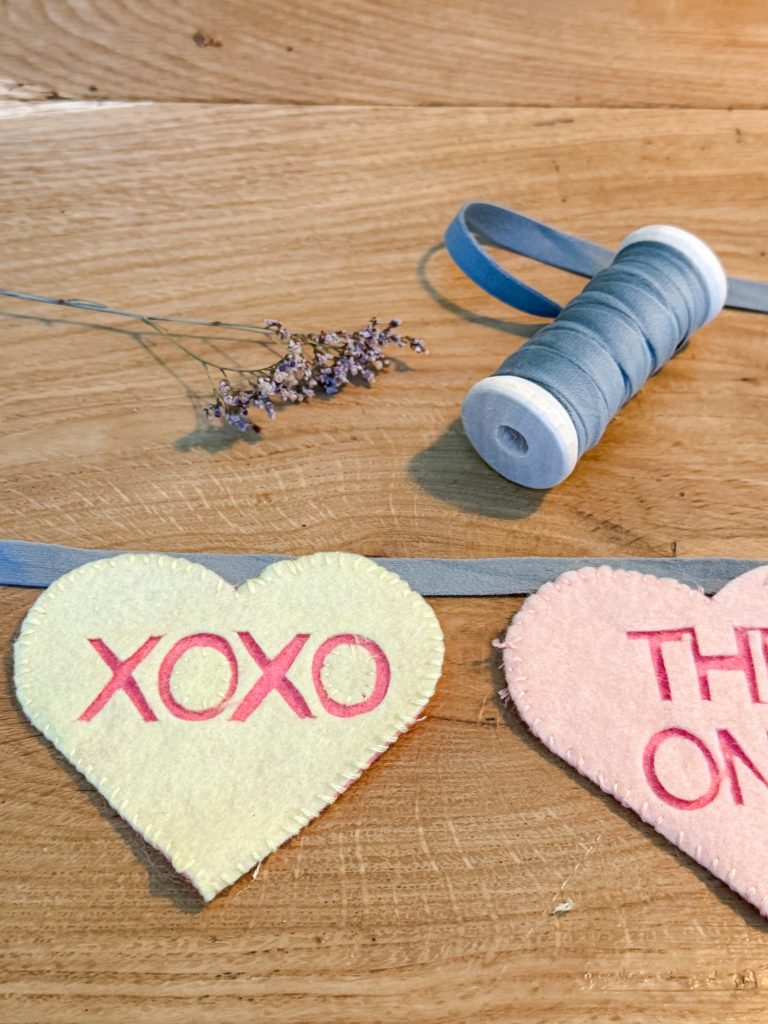 Felt valentine heart banner being attached to a velvet ribbon